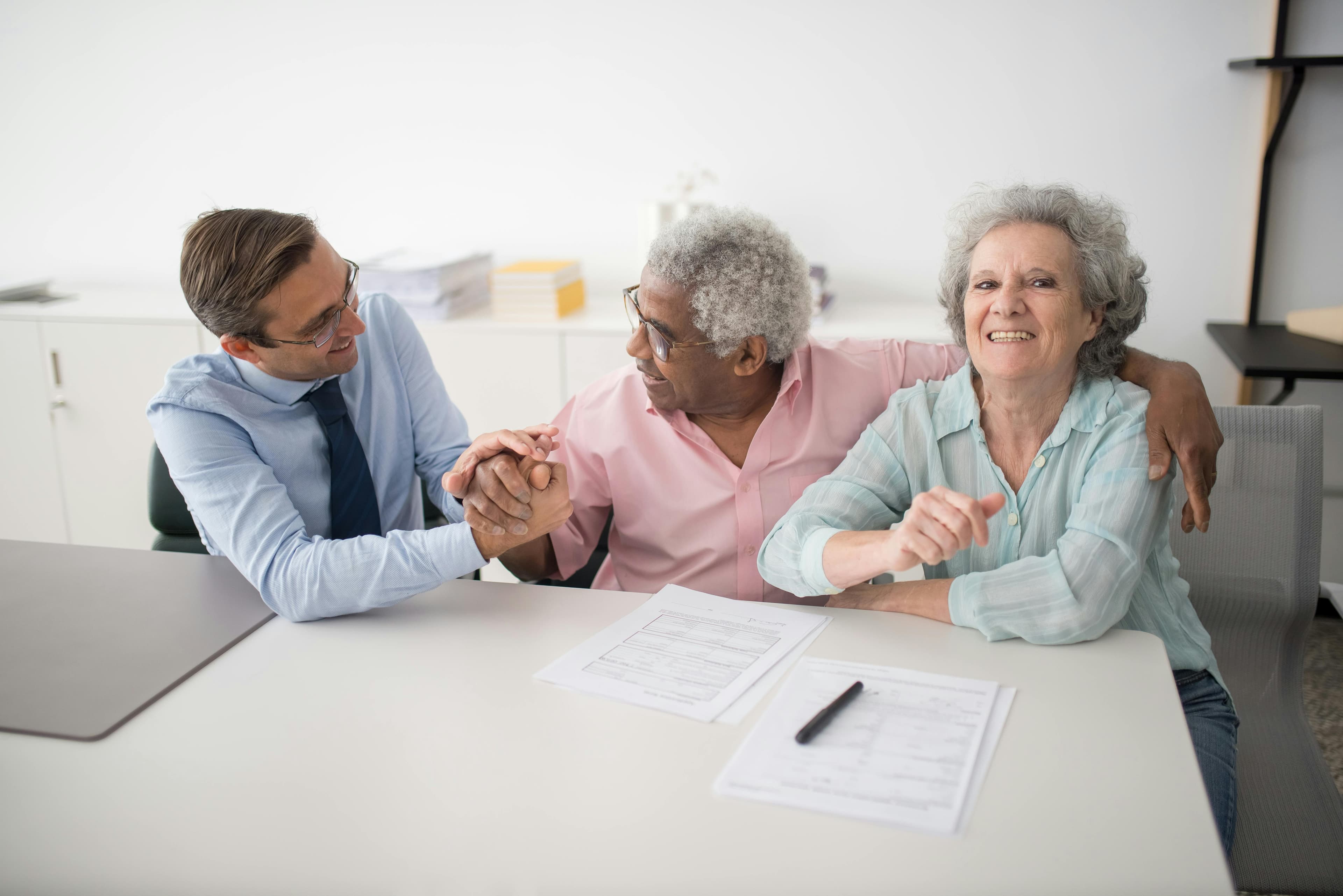 An advisor reviewing paperwork with an older couple at a kitchen table