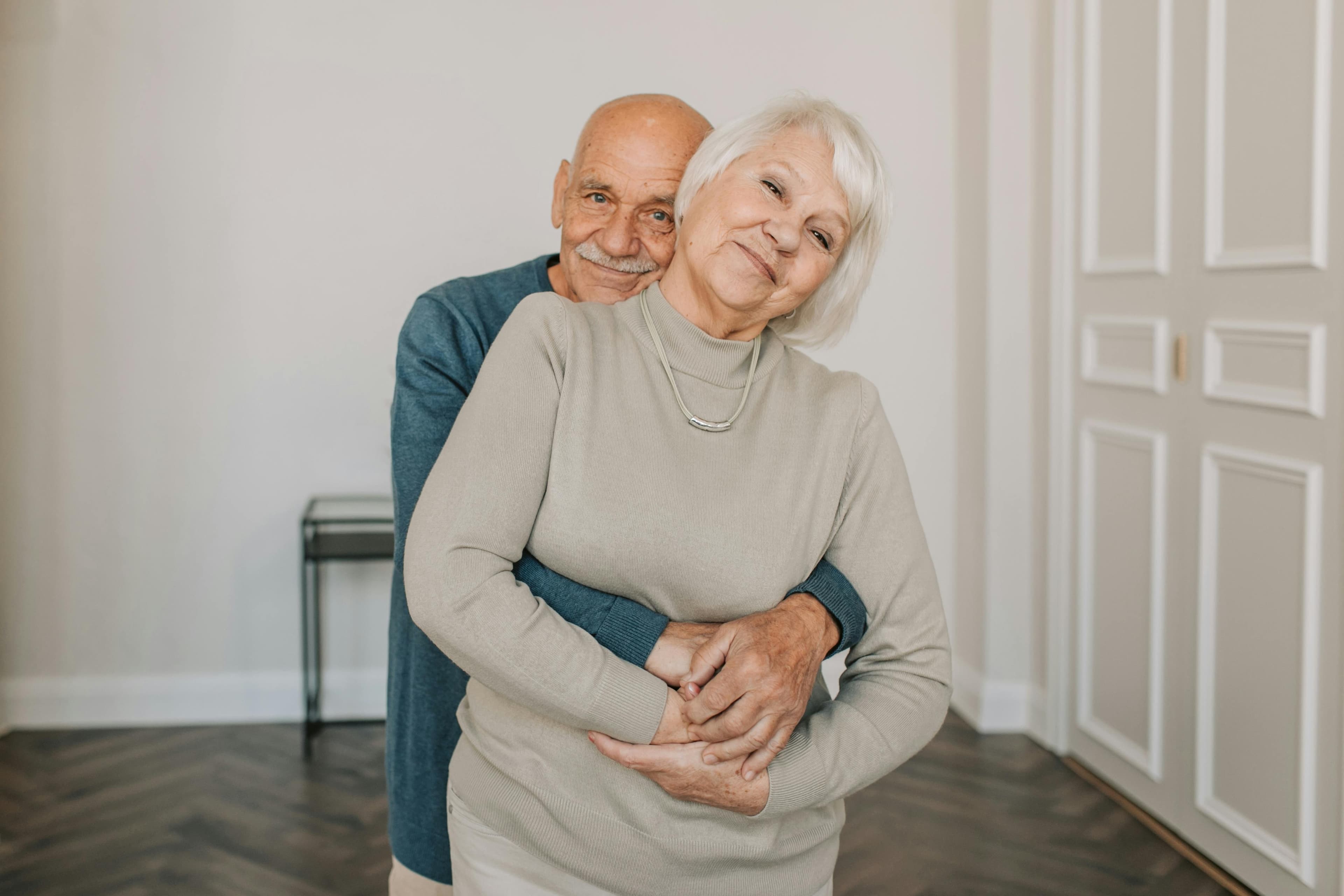 An elderly couple embracing at home